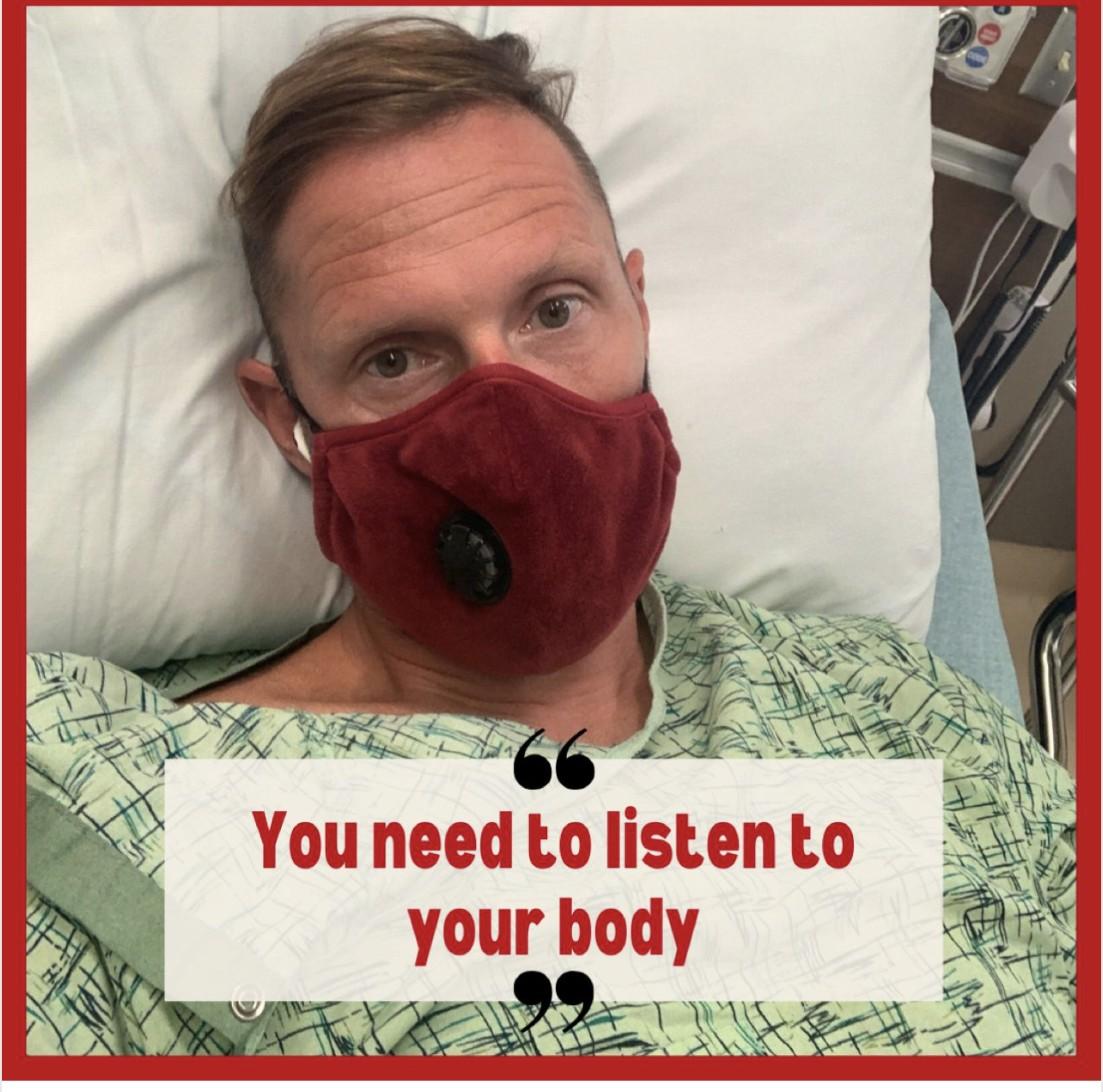Wayne Partello lying in a hospital bed wearing a face mask, with text overlay reading "You need to listen to your body."