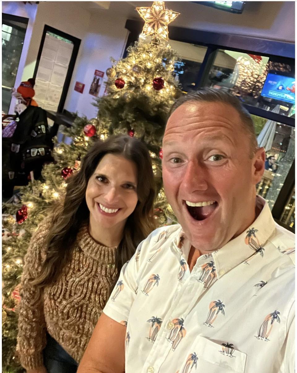 Wayne Partello and his wife Katie in front of a Christmas tree, celebrating one year of CUENTO Marketing.