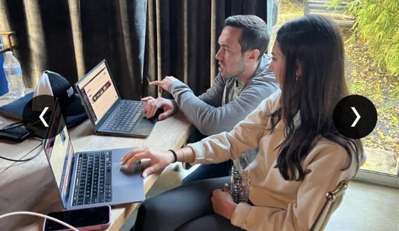 Two CUENTO teammates working on laptops together during the retreat.
