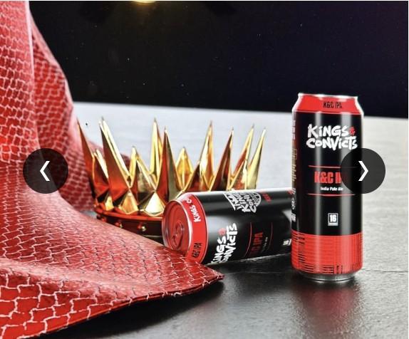 Gold spiked crown prop beside Kings & Convicts K&C IPA beer cans and red snakeskin fabric.