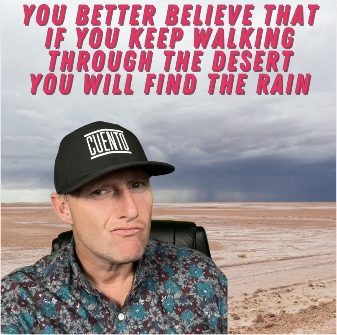 CUENTO meme graphic of Wayne wearing a CUENTO cap, composited over a stormy desert landscape, captioned 'You better believe that if you keep walking through the desert you will find the rain.'