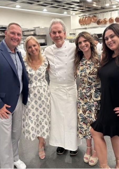 Wayne and four friends posing with a chef in a restaurant kitchen.
