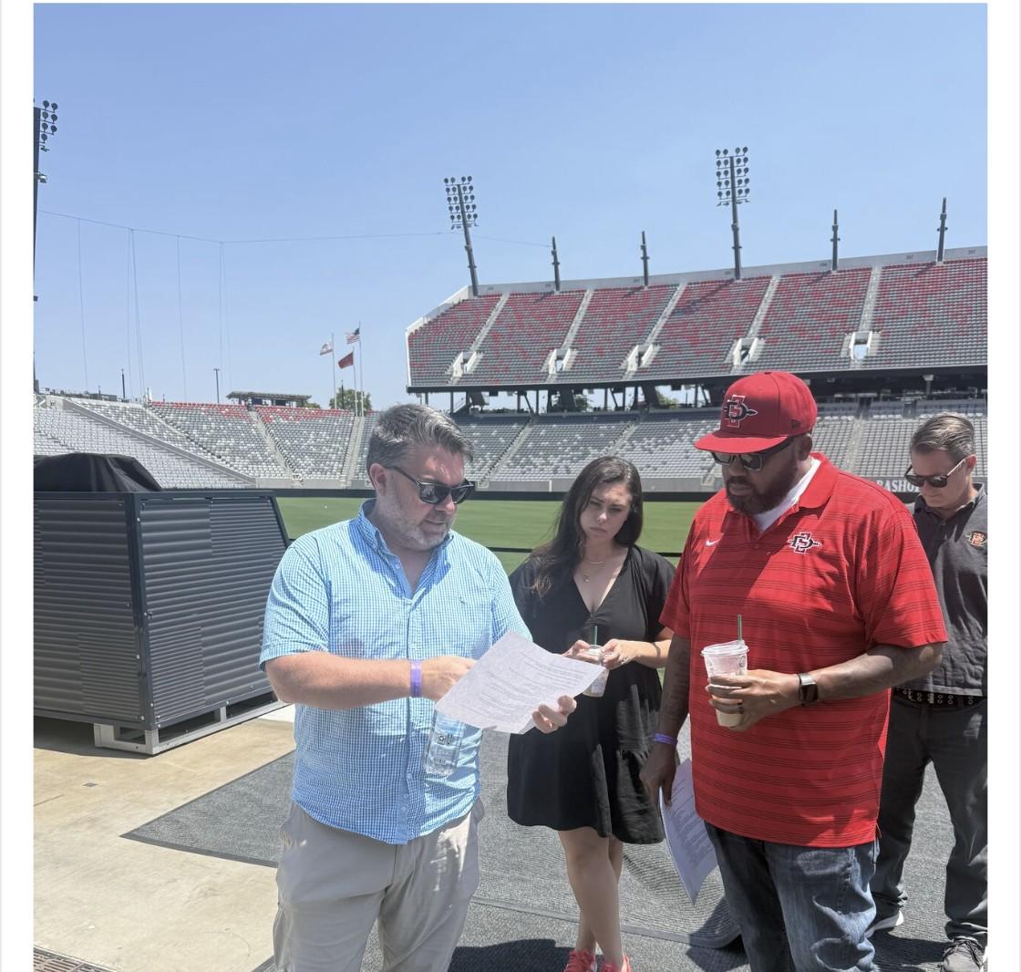 CUENTO's Matt Coy reviewing notes with SDSU Athletics staff on the field at Snapdragon Stadium