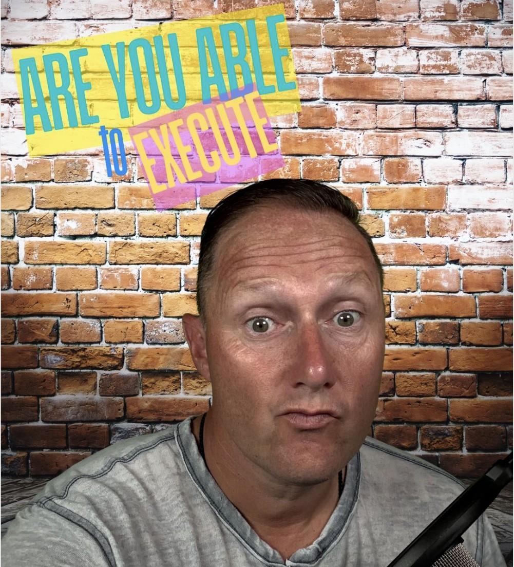 Wayne Partello taking a close-up selfie in front of a brick wall with a microphone visible, captioned 'Are You Able to Execute'