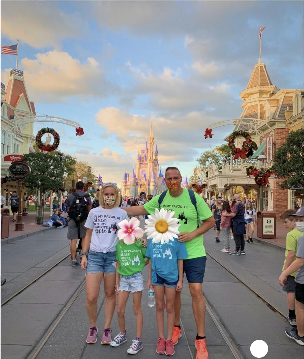 Wayne and his family posing on Main Street in front of Cinderella Castle at Walt Disney World, wearing masks and matching 'In My Favorite Place With My Favorite People' shirts, with the children's faces covered by decorative flower graphics.